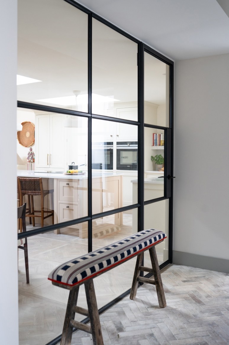 Black steel-framed glazed screen with bench on herringbone brick tile floor