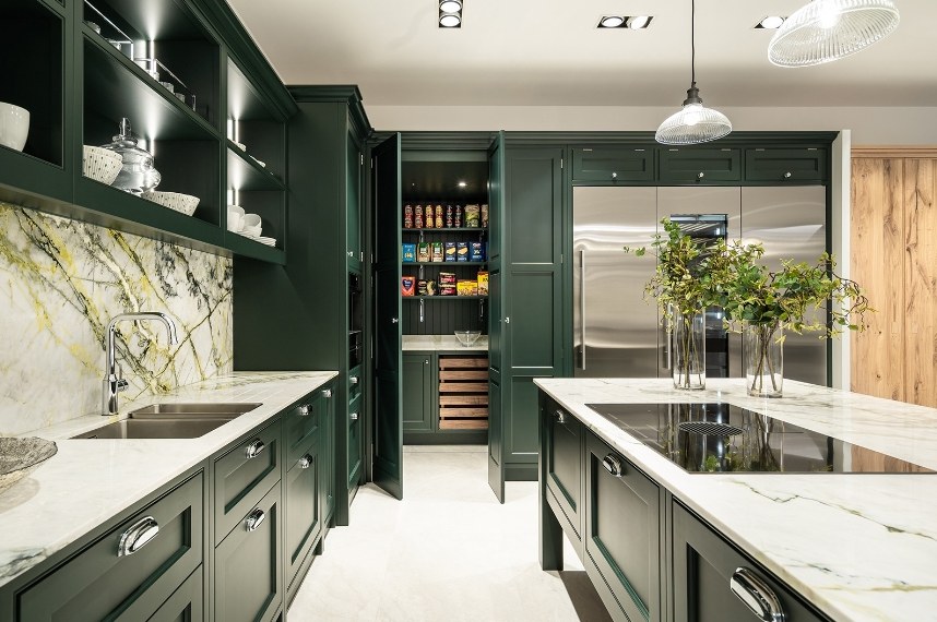 Green kitchen with open pantry doors and marble worktops